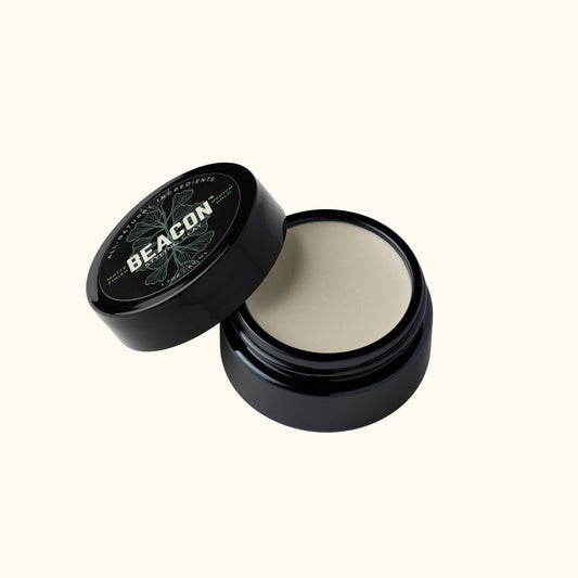 Open glossy black jar of Beacon Styling Clay showing thick matte hair clay, medium hold natural styling product, water based and unscented.